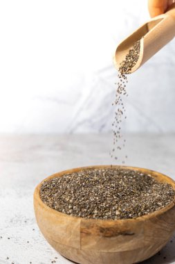 Chia tohumları tahta kaseye düşer. Omega 3 yağ asitleri bakımından zengin sağlıklı süper yiyecekler. Kuru, sağlıklı, doğal bileşen. Chia taneleri düşüyor. Vejetaryen yemeği. 