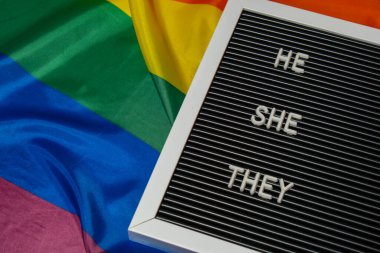 HE SHE THEY text Neo pronouns concept on Rainbow flag background gender pronouns. Non-binary people rights transgenders. Lgbtq community support assume my gender, respect pronouns tolerance equal clipart