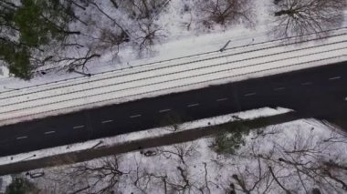 Kış zamanı yolda dönen hava manzarası, orman ağaçlarıyla çevrili yol. Kırsal kış bölgesi. Üst manzara manzarası. İHA 'dan ateş etmek. Kış ormanlarında yol karla kaplıydı. Yol gökyüzünden görünüyor.