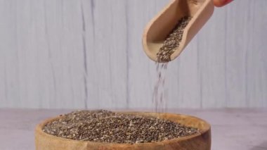 Slow motion chia seeds fall in wooden bowl. Healthy superfood rich in Omega 3 fatty acids. Dry healthy natural ingredient. Chia grains are falling. Vegetarian food 