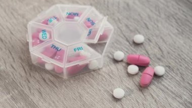 Organizatör haftalık çekimlerini büyüt. Günlük haplarla birlikte tıbbi hap kutusunu kapat. İlaçları beyaz pembe haplar ve kapsüllerle al. Evde günlük vitaminler. İlaç besin takviyeleri