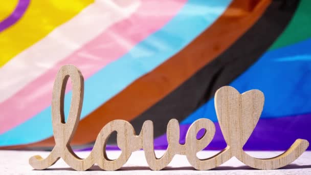 絹の素材で作られたレインボーLgbtqiaフラグ上の心のロマンスと木製の言葉の愛をズームアウト バレンタインデーのグリーティングカード Lgbtqプライド月間のシンボル 平等な権利 平和と自由 サポート — ストック動画