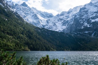 Polonya Tatry dağlarındaki Morskie Oko Gölü Karlı Dağ Kulübesi, Zakopane, Polonya. Güzel yeşil tepeler ve kara bulutlar içindeki dağlar ve Morskie Oko Gölü 'nün yansıması. Seyahat eden turist