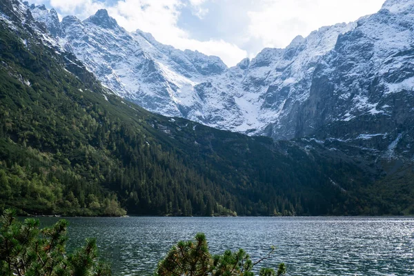 Morskie Oko lake Snowy Mountain Hut in Polish Tatry mountains, Zakopane, Poland. Beautiful green hills and mountains in dark clouds and reflection on the lake Morskie Oko lake. Travel tourist