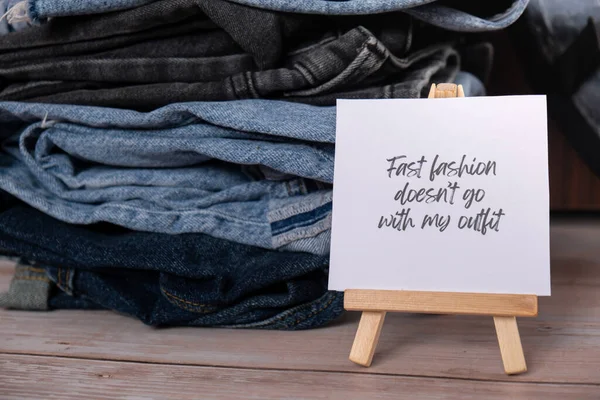 FAST FASHION DOESNT GO WITH MY OUTFIT text on paper note on Jeans clothes assortment Second hand sustainable shopping. Capsule minimal wardrobe. Sustainable fashion overconsumption, conscious buying