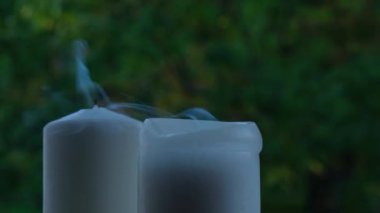 White candle burns candlestick White burning candle with blazing flames. Tongues of fire on green trees background. Home cozy atmosphere Healing reflection stress relief activities Romantic mood