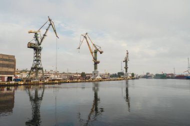 Motlawa river to Baltic Sea. Coal mine, polluting environment by the river POV from ferry swimming on river canal. Industrial building at the Gdansk Shipyard. Prefabrication workshop and heavy cranes