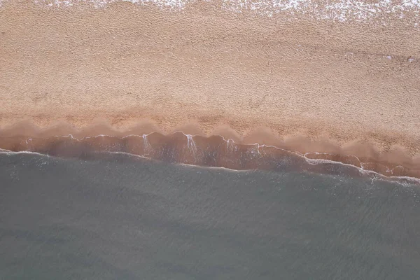 Winter in cold Baltic sea snowy beach in Gdansk. Aerial view of snow covered beach and dunes and dark calm sea nature landscape captured with drone. Winter tourism in Poland