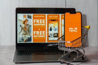 Gdansk, Polonya - Mart 2023 Temu uygulama simgesi MacBook Apple bilgisayar dizüstü bilgisayarı ve alışveriş arabalı cep telefonu ekranında. Çin merkezli Pinduoduo e-ticaret platformunun Temu yan kuruluşu. İnternetten alışveriş