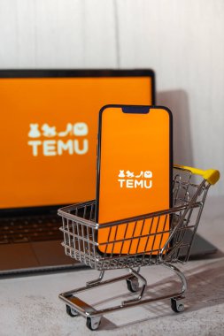 Gdansk, Polonya - Mart 2023 Temu uygulama simgesi MacBook Apple bilgisayar dizüstü bilgisayarı ve alışveriş arabalı cep telefonu ekranında. Çin merkezli Pinduoduo e-ticaret platformunun Temu yan kuruluşu. İnternetten alışveriş