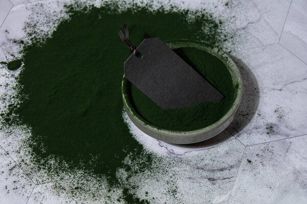 Blue-green algae Chlorella and spirulina powder in bowl with empty paper note mock up copy space. Super powder. Natural supplement of algae. Detox superfood drink cocktail. Food supplement source of
