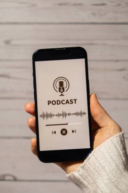 Elinde cep telefonu olan tanınmayan bir kadın internet sitesi uygulamasını kablosuz kulaklıkla dinliyor. Ses iyileştirme, ses terapisi sağlık ritüelleri, olumlu ruh sağlığı alışkanlıkları.