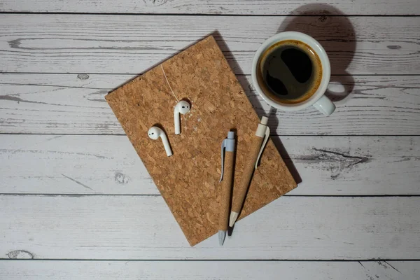 stock image Top view, wooden Office desk with cup of coffee, eco pen, wireless headphones and recycle notebook. Business or student workspace concept Flat lay. Personal diary Audio healing, sound mental health