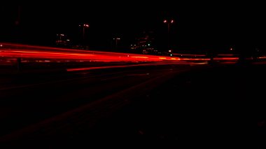 Geceleri arabaların ışıkları. Sokak lambaları. Gece Karayolu Şehri. Uzun pozlu fotoğraf gece yolu. Yoldaki renkli kırmızı ışık şeritleri. Arkaplan duvar kağıdı odaklı olmayan fotoğraf. 