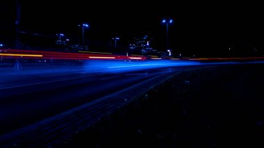 Geceleri arabaların ışıkları. Sokak lambaları. Gece Karayolu Şehri. Uzun pozlu fotoğraf gece yolu. Yoldaki renkli kırmızı ışık şeritleri. Arkaplan duvar kağıdı odaklı olmayan fotoğraf. 