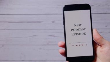 Elinde cep telefonu olan tanınmayan bir kadın. YENİ PODCAST EPISODE. Kablosuz kulaklıklı web sitesi uygulaması. Ses iyileştirme, ses terapisi sağlık ritüelleri, pozitif ruh sağlığı.