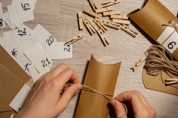 stock image Unrecognizable young woman sticks number on craft bag, fastens with clothespin. Female making kraft paper for homemade advent calendar Made with your own hands step by step DIY crafts do it yourself