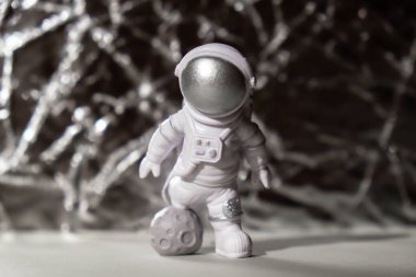 Plastic toy figure astronaut on silver background Copy space. Concept of out of earth travel, private spaceman commercial flights. Space missions and Sustainability