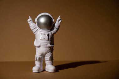 Plastic toy figure astronaut on beige neutral background Copy space. Concept of out of earth travel, private spaceman commercial flights. Space missions and Sustainability
