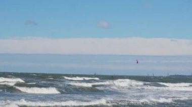 Wing Foiling uçurtmaları, rüzgar sörfü Baltık Denizi 'nde açık havada su sporu. Koyu mavi bulutlar, okyanus yüzeyinde fırtına öncesi köpük dalgaları, dramatik deniz manzarası.. 