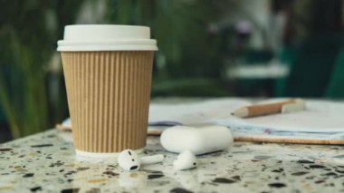Yakınlaştır kahveyi kağıt bardağa koy kağıt defter ve kablosuz kulaklıkla birlikte. Model kahve molası. Ses iyileştirme, ses terapisi sağlık ritüelleri, pozitif ruh sağlığı.