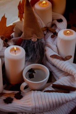 Thanksgiving and Hello Fall Halloween concept Celebrating autumn holidays at cozy home on the windowsill Hygge aesthetic atmosphere Autumn leaves gnome, spices and candle on knitted white sweater in clipart