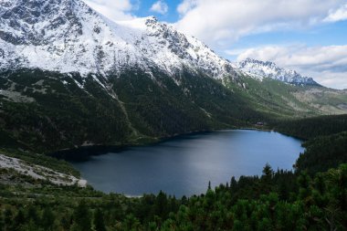 Polonya Tatry dağlarındaki Morskie Oko Karlı Dağ Kulübesi, insansız hava aracı manzarası, Zakopane, Polonya. Güzel yeşil tepelerin ve dağların kara bulutlardaki görüntüsü ve Morskie Oko Gölü 'nün yansıması.