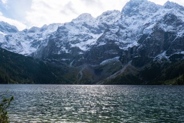 Polonya Tatry dağlarındaki Morskie Oko Gölü Karlı Dağ Kulübesi, Zakopane, Polonya. Güzel yeşil tepeler ve kara bulutlar içindeki dağlar ve Morskie Oko Gölü 'nün yansıması. Seyahat eden turist