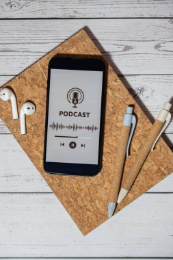 Kâğıt defter kalemleri, kablosuz kulaklıklar ve cep telefonu Podcast dinleme sitesi uygulama uygulamaları. Ses iyileştirme, ses terapisi sağlık ritüelleri, olumlu ruh sağlığı alışkanlıkları. Millenial