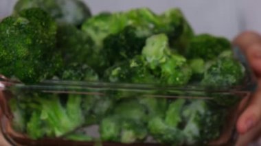 Tanımlanamayan bir kadın, dondurulmuş yemek brokolisine ev yapımı brokoli gösteriyor. Hasat konsepti. Kış için sebze depolamak sağlıklı yiyecekler, yemek malzemeleri.