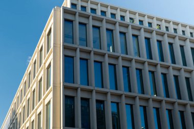 Gökyüzü arka planında cam cepheli modern ofis binası. Sarı süslemeli şeffaf cam ofis duvarı. Modern Avrupa binasının dış cephesi