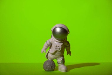 Plastic toy astronaut on green chroma key background Template Mock up Copy space. Concept of out of earth travel, private spaceman commercial flights. Space missions and Sustainability