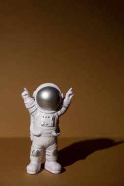 Plastic toy figure astronaut on beige neutral background Copy space. Concept of out of earth travel, private spaceman commercial flights. Space missions and Sustainability