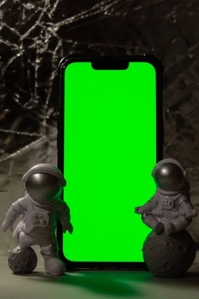 塑料玩具形象宇航员与手机彩色键绿色屏幕为您的广告复制空间 走出地球旅行的概念 私人航天人商业飞行 空间飞行任务和 — 图库照片