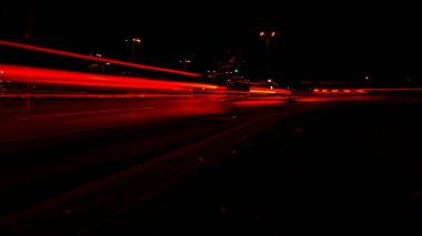 Geceleri arabaların ışıkları. Sokak lambaları. Gece Karayolu Şehri. Uzun pozlu fotoğraf gece yolu. Yoldaki renkli kırmızı ışık şeritleri. Arkaplan duvar kağıdı odaklı olmayan fotoğraf. 