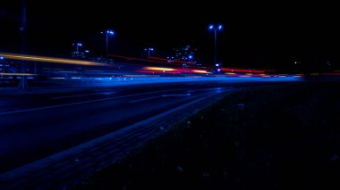 Geceleri arabaların ışıkları. Sokak lambaları. Gece Karayolu Şehri. Uzun pozlu fotoğraf gece yolu. Yoldaki renkli kırmızı ışık şeritleri. Arkaplan duvar kağıdı odaklı olmayan fotoğraf. 