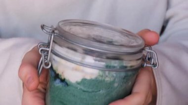 Cam kavanoz yiyen tanınmayan bir kadın doğal organik yoğurt ve yabanmersini spirulina klorella süper yiyecek süper tozu mavi deniz yosunu. Chia tohumları puding bağışıklık güçlendirici bileşenler