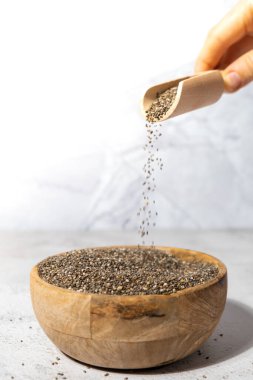 Chia tohumları tahta kaseye düşer. Omega 3 yağ asitleri bakımından zengin sağlıklı süper yiyecekler. Kuru, sağlıklı, doğal bileşen. Chia taneleri düşüyor. Vejetaryen yemeği. 