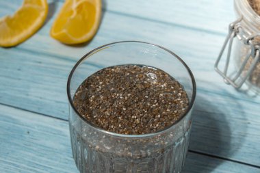 Preparing superfood water drink rich in Omega 3 fatty acids. Pouring coconut water. Adding soaked chia seeds and lemon detox Breakfast. Clean eating, weight loss, dieting food concept Vegetarian