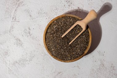 Tahta kaşıkla tahta kasede Chia tohumları. Omega 3 yağ asitleri bakımından zengin sağlıklı süper yiyecekler. Kuru, sağlıklı, doğal bileşen. Chia taneleri düşüyor. Vejetaryen yemeği. 