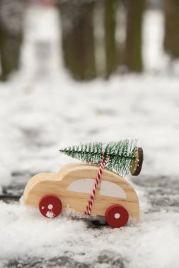 Karda Noel ağacı taşıyan ahşap bir araba. Karlı arazide oyuncak araba için uzayı kopyala. Mutlu Noeller ve mutlu yıllar konsepti. Kış geliyor. Tebrik kartı.