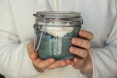 Doğal organik yoğurt ve yabanmersini spirulina klorella süper yiyecek süper tozu mavi deniz yosunuyla cam kavanoz yiyen tanınmamış bir kadın. Bağışıklık güçlendirici bileşenler. Konsept