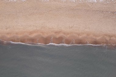 Winter in cold Baltic sea snowy beach in Gdansk. Aerial view of snow covered beach and dunes and dark calm sea nature landscape captured with drone. Winter tourism in Poland