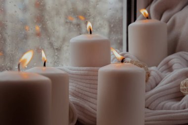 Sonbahar tatili konsepti. Pencere kenarındaki Hygge estetik atmosferinde örgü örülmüş beyaz süveterin üzerinde rahat bir evde. Mikro anın sakin yaşamı yavaş yavaş yaşanır. Ruhsal sağlık.