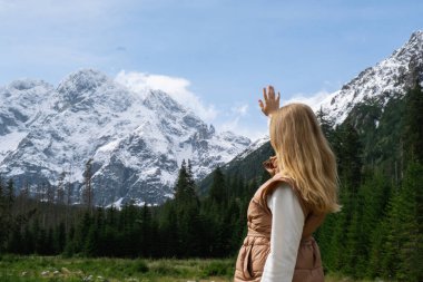 Polonya 'nın Tatry dağları Zakopane Polonya' daki Morskie Oko Karlı Dağ Kulübesi 'nde doğanın tadını çıkaran genç bir kadın. Doğanın estetik güzellikteki yeşil tepeleri. Zihinsel ve fiziksel refah açık havada seyahat eder.