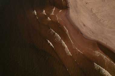 Dalgaların, deniz kıyılarının insansız hava görüntüsü. Kumsallar ve kumullar, sakin deniz dalgaları insansız hava aracıyla ele geçirilen doğa manzarası. Polonya 'da turizm