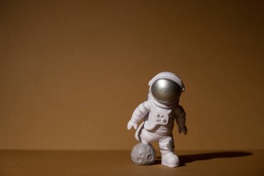Plastic toy figure astronaut on beige neutral background Copy space. Concept of out of earth travel, private spaceman commercial flights. Space missions and Sustainability