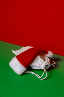 Noel Baba şapkası, Noel Baba 'nın hediye çantasıyla dolu, izometrik kırmızı arka planda. Metnin için alanı kopyala. Reklam için hazırlan. Tatil Noel kompozisyonu. Minimalist tebrik kartı