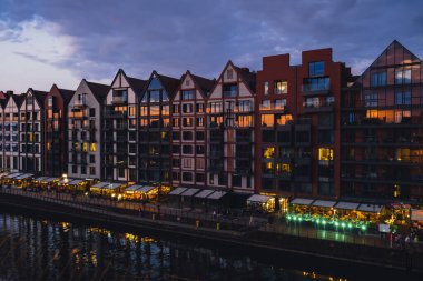 Gdansk 'ta eski bir kasaba, Polonya' nın alacakaranlığında. Gdansk Place 'de kalıp Motlawa nehri üzerindeki Wyspa Spichrzow Travel' de yemek yemek için yeni modern mimari binaların penceresinden gün batımını izliyoruz.