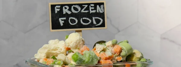 Frozen mixed vegetables for long-term storage with blackboard label and text FROZEN FOOD. Deep freezing of vegetables. defrosting Frozen food vegetables background